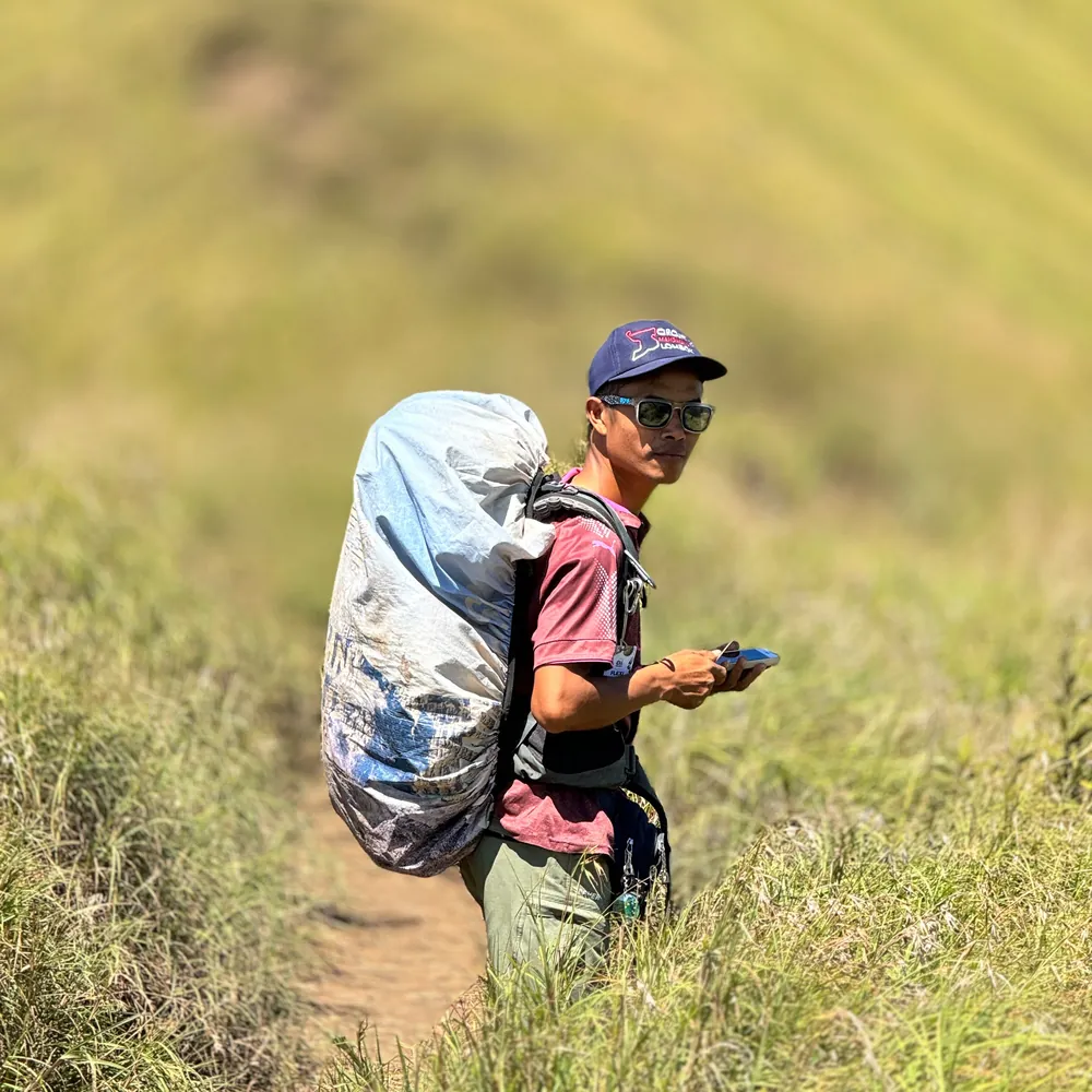 Rindu on the trail on Mount Rinjani, carrying a load and looking at the camera